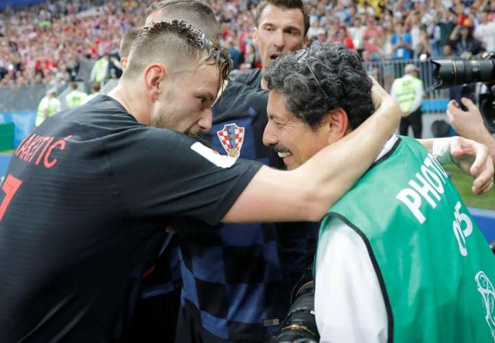 El jugador de Croacia Ivan Rakitic (izq.) se disculpa después de chocar con el fotógrafo Yuri Cortez en la celebración del gol de Mario Mandzukic durante el partido de semifinal del Mundial 2018. Fotos EFE