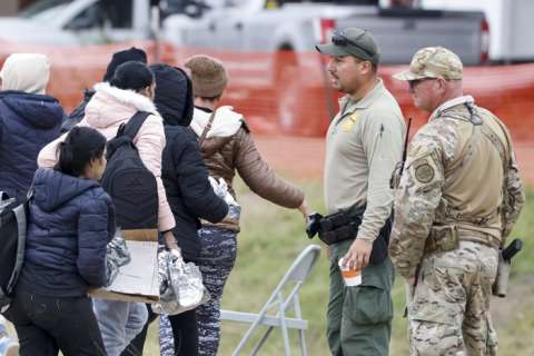 Un grupo de migrantes (i) que pasa junto a agentes de la Patrulla Fronteriza (c) y de la Guardia Nacional de Texas (d), en Shelby Park en Eagle Pass, Texas (EE.UU.). EFE / Archivo