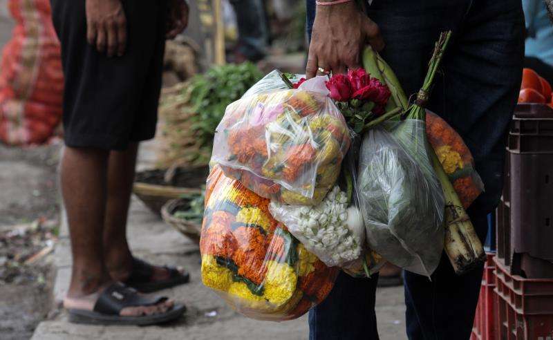 Un hombre porta flores en bolsas de plástico en el mercado de Dadar, en Bombay (India), hoy, 22 de junio de 2018. EFE