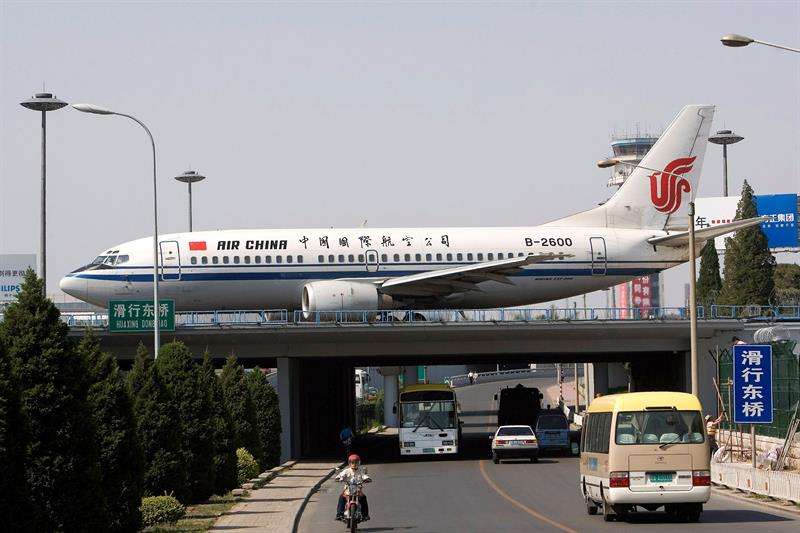 Un avión de las aerolineas Air China circula por una pista de aterrizaje mientras otros vehículos lo hacen por una autopista, en Pekín, China. EFE/Archivo