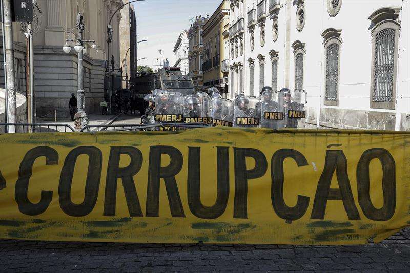 Policías brasileños vigilan una protestas frente a la Asamblea de Río de Janeiro (Brasil), donde los legisladores debatían el pasado viernes sobre el futuro del presidente de la institución y varios diputados, encarcelados por corrupción. EFE