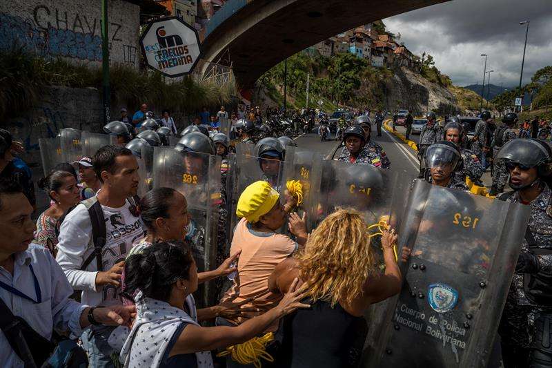 Un grupo de personas protesta frente a miembros de la Policía Nacional Bolivariana (PNB) hoy, jueves 28 de diciembre del 2017, en Caracas (Venezuela). EFE