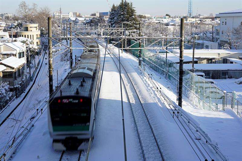 Un tren circula por la vías después de una fuerte nevada en Tokio. EFE