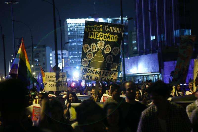 Manifestantes muestran carteles alusivos a la clase política peruana durante multitudinaria marcha contra del indulto humanitario a Fujimori en la oscuridad de la avenida Garu, donde según denunciaron manifestantes el alumbrado público fue apagado. EFE