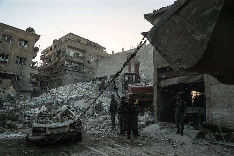 Trabajadores del departamento de Defensa Civil sirio retiran escombros para tratar de localizar a las personas desaparecidas en el derrumbe de un edificio tras el bombardeo registrado ayer en Duma (Siria). EFE