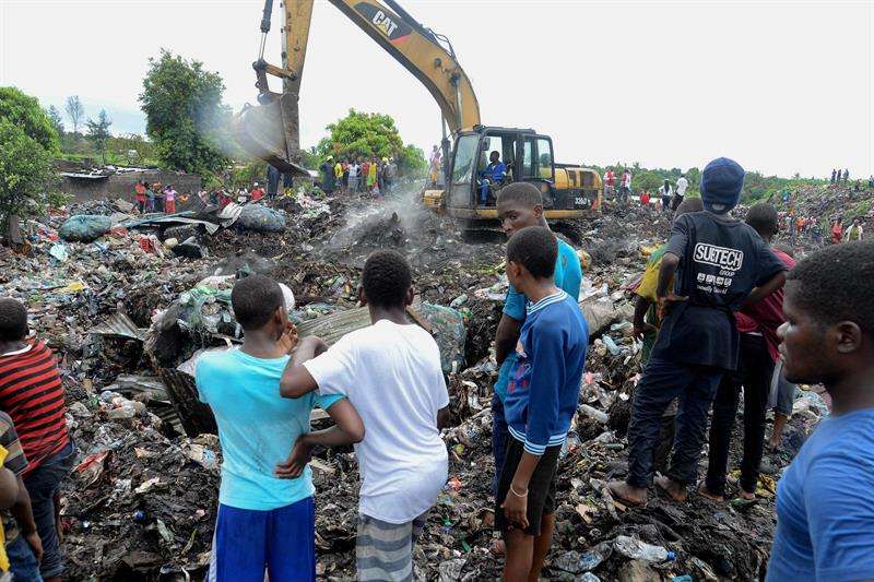 Varias personas observan las labores de búsqueda de los servicios de emergencia en un basurero de Maputo (Mozambique) este 19 de febrero. EFE
