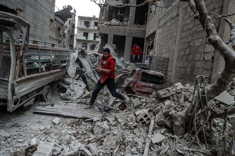 Un voluntario de Media Luna Roja corre tras un bombardeo en Duma, feudo rebelde de Guta Oriental (Siria). EFE