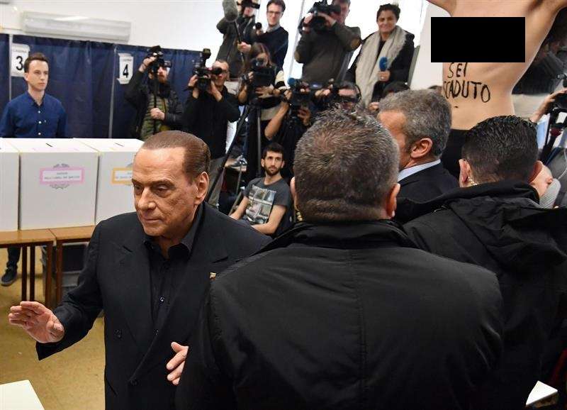 Exprimer ministro italiano y líder del partido &#039;Forza Italia&#039;, Silvio Berlusconi (izq.), Deja la mesa de votación cuando un activista &#039;Femen&#039; (R) presenta una protesta con el torso desnudo durante la votación en las elecciones generales. EFE