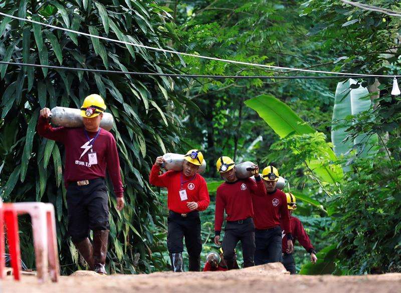Miembros de los servicios de rescate cargan con botellas de oxígeno mientras continúan las labores de rescate de los doce menores y un adulto atrapados en una cueva en el parque de Khun Nam Nang (Tailandia) . EFE