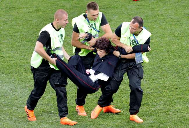 Miembros de seguridad reducen a un espontáneo que saltó al campo durante el partido Francia-Croacia. Foto:EFE