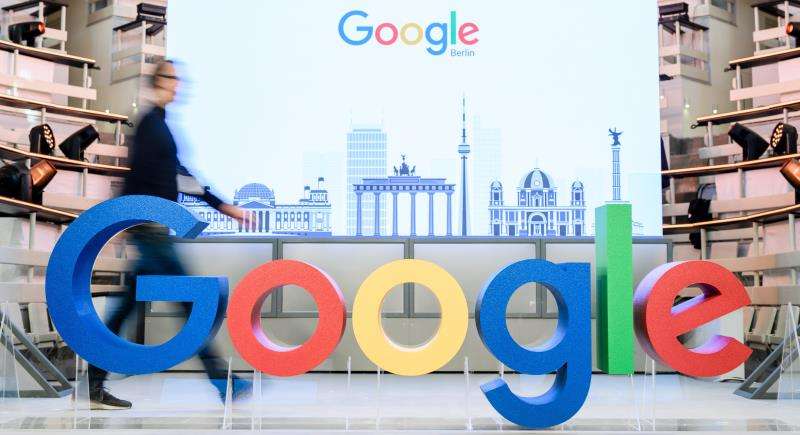 Un empleado camina junto al logotipo de la multinacional estadounidense Google. EFE/Archivo
