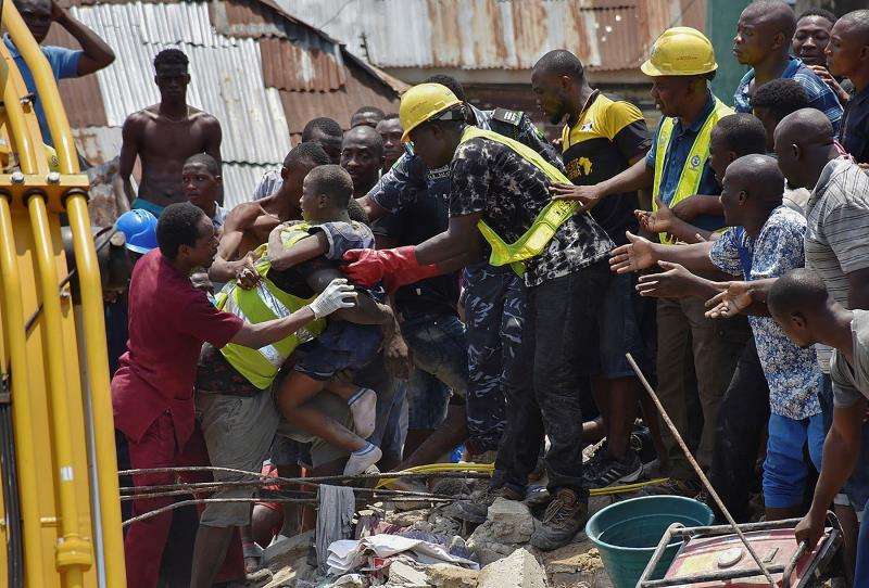 Operarios rescatan a un niño entre los escombros tras derrumbarse un edificio este miércoles en Lagos, Nigeria. EFE