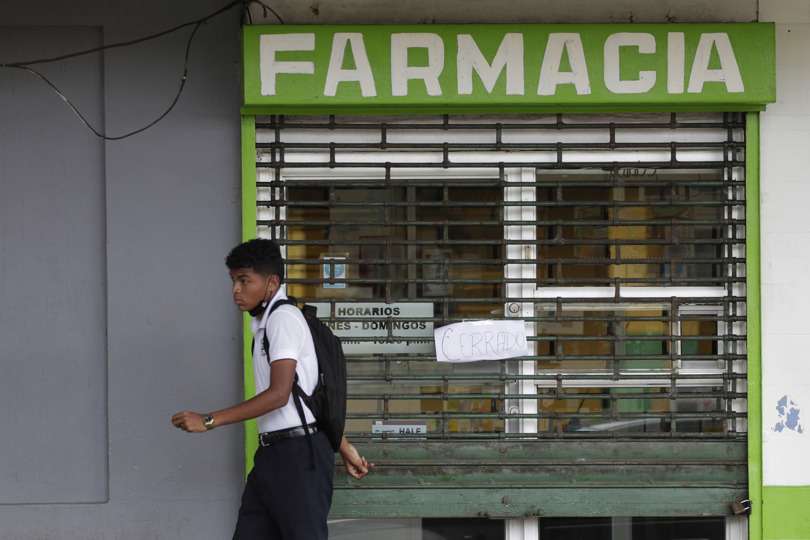 Una persona camina frente a una farmacia cerrada en La Chorrera, Panamá. EFE