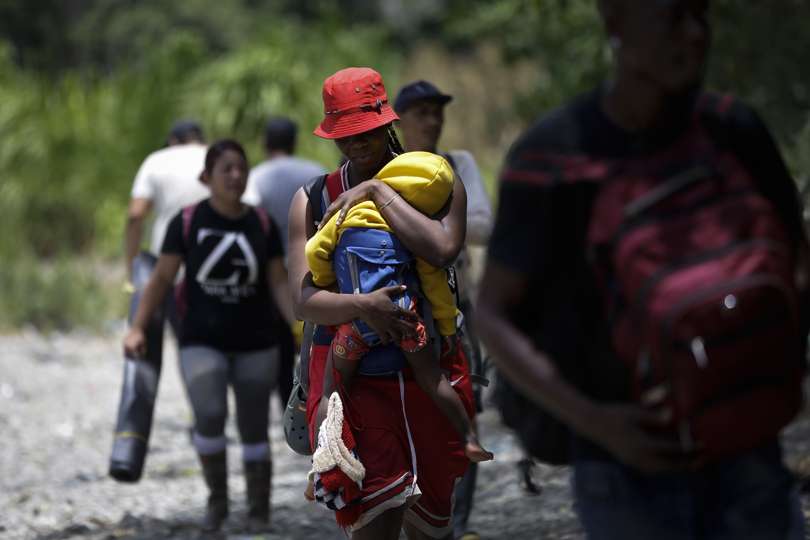 Una mujer migrante carga a su hijo en la selva mientras esperan para ser trasladados en canoa desde la Quebrada León hasta la comunidad de Bajo Chiquito, en Darién. EFE