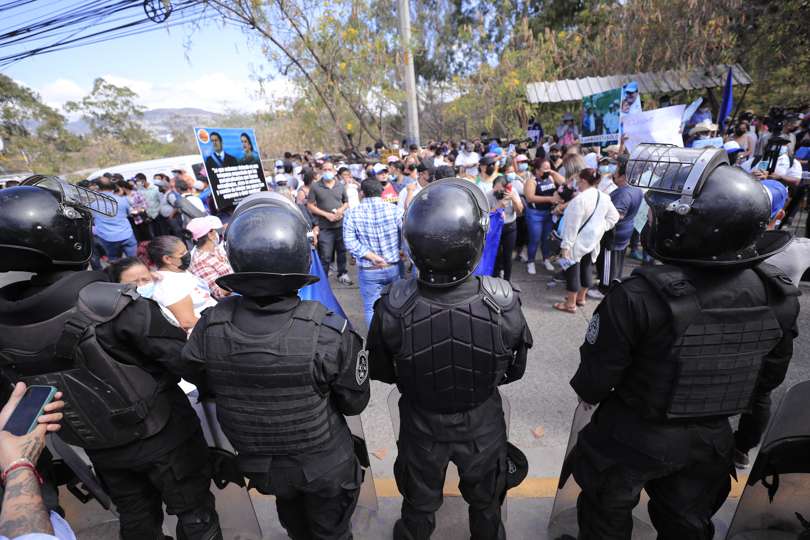 Miembros de la policía vigilan a simpatizantes del expresidente de Honduras Juan Orlando Hernández que se reúnen a las afueras de la Corte Suprema de Justicia. EFE