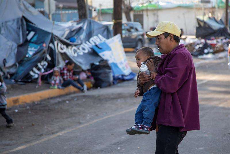 Migrantes permanecen hoy a la intemperie fuera del albergue original que resultó inhabitable luego de las fuertes lluvias en Tijuana (México). EFE