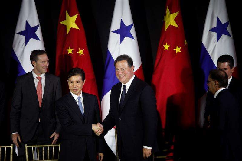 El ministro de Comercio de China, Zhong Shan (I), estrecha la mano al presidente de Panamá, Juan Carlos Varela (C), tras firmar un acuerdo de estudios de factibilidad para un sistema ferroviario y la suscripción de un TLC, el 7 de diciembre de 2017. EFE