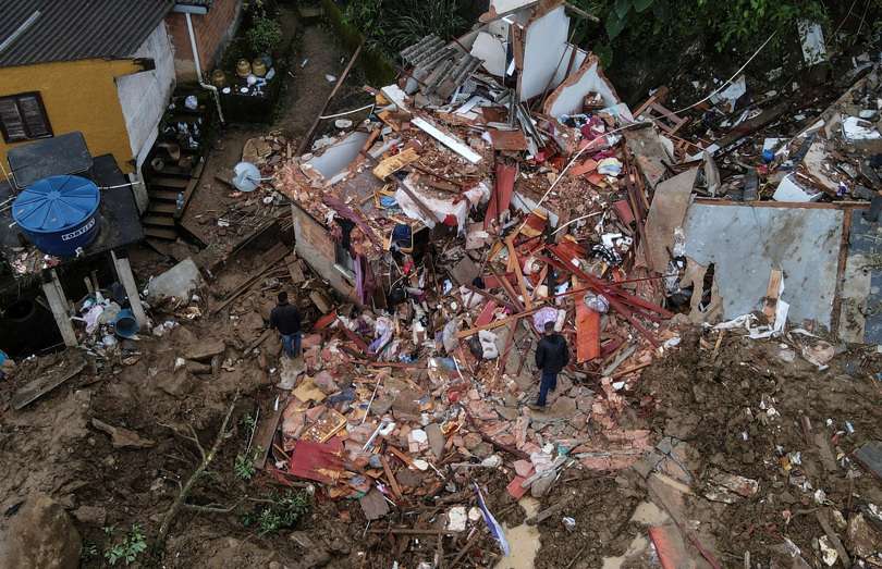 Fotografía tomada con un drone que muestra a 2 hombres junto a una vivienda destrozada en medio de la destrucción tras las fuertes lluvias del martes en el Morro de la Oficina, en la ciudad de Petrópolis, estado de Rio de Janeiro. EFE