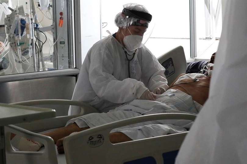 Una empleada de la salud atiende a un paciente en una unidad de cuidados intensivos para enfermos de covid-19. EFE