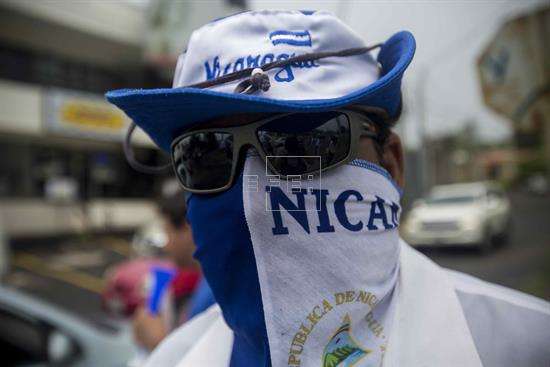 Un joven con la bandera de Nicaragua envuelta en la cara participa en un plantón frente a las instalaciones del Consejo Superior de la Empresa Privada (Cosep) en Managua (Nicaragua). EFE