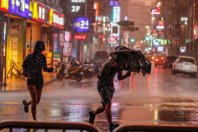 Un chico lucha con su paraguas bajo un fuerte chaparrón por el paso del tifón María en Taipei, Taiwán. EFE