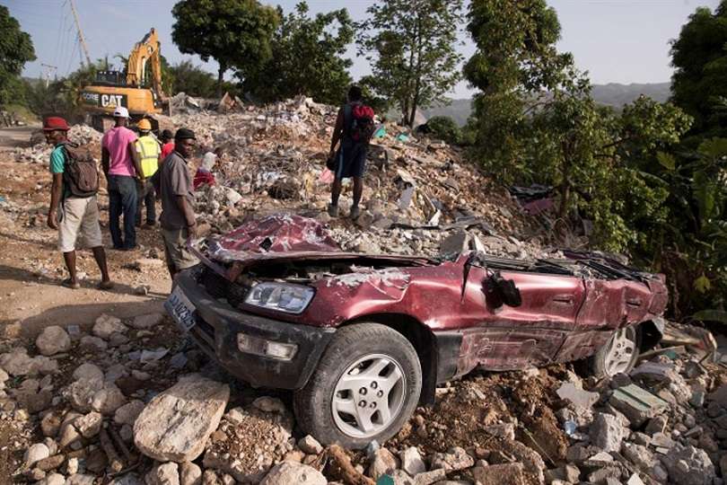 arias personas permanecen cerca de un vehículo aplastado por la caída de un muro durante el terremoto del pasado 14 de agosto, hoy, en Marceline (Haití). EFE