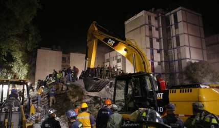 Las labores de búsqueda continuaron durante la noche. Camiones llenos de voluntarios armados con picos y palas recorrían las calles oscuras de la capital mexicana. AP