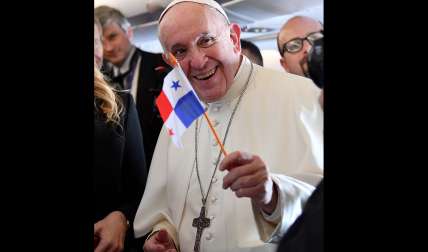 El papa Francisco (d) ondea una bandera panameña en el avión que le traslada este miércoles a Panamá. EFE