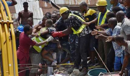 Operarios rescatan a un niño entre los escombros tras derrumbarse un edificio este miércoles en Lagos, Nigeria. EFE